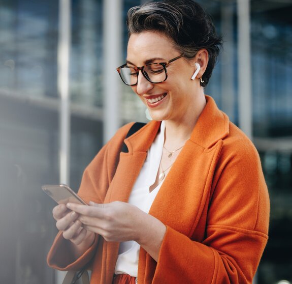 Smiling businesswoman reading a text message on her phone while commuting to her office in the city