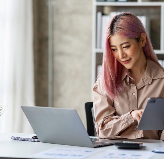 Portrait of a young Asian businesswoman working on a tablet with a laptop at the thinking office. analyze marketing data online business ideas.