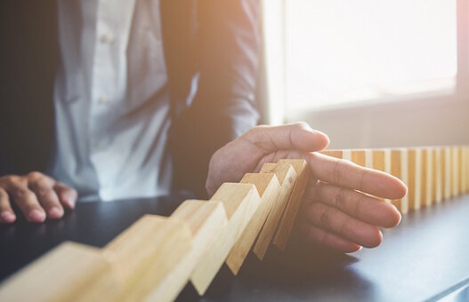 Problem Solving,Close up view on hand of business woman stopping falling blocks on table for concept about taking responsibility.