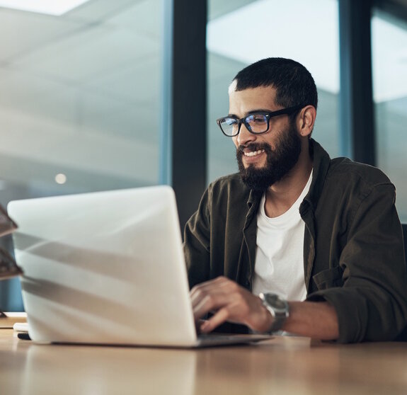 Smile, work and a businessman with a laptop for an email, communication or online coding. Happy, programming and a male programmer typing on a computer for web or software development in an office