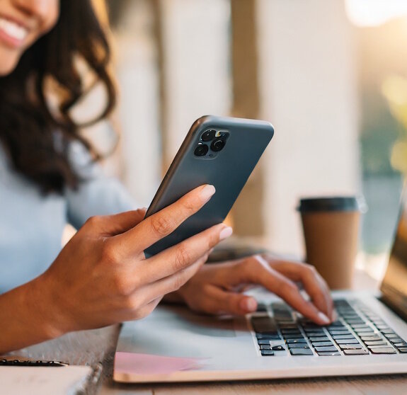 Woman using smartphone and working at laptop computer.