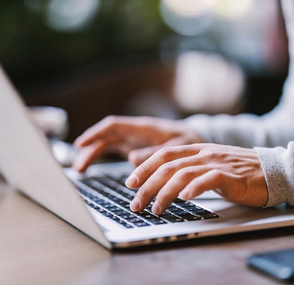 Close up of hands typing on a laptop.