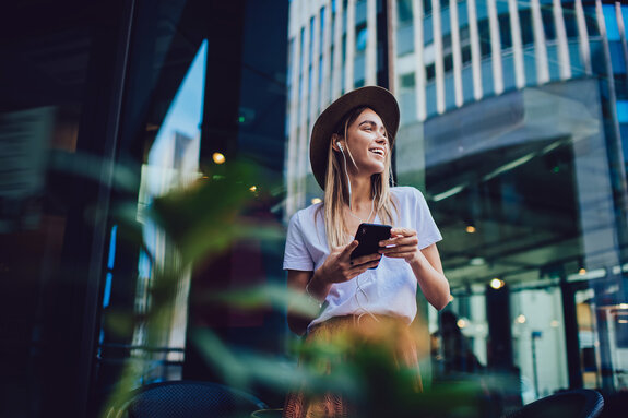 Cheerful woman listening to music in cafe