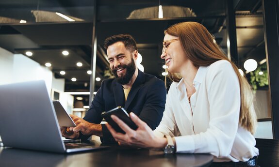 Smiling entrepreneurs using wireless technology together