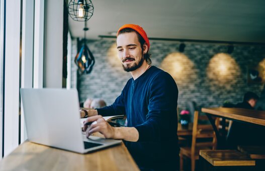 Positive caucasian male checking news from networks working remotely on publicity area, man freelancer reading information on web page looking on screen of laptop computer connected to wifi internet