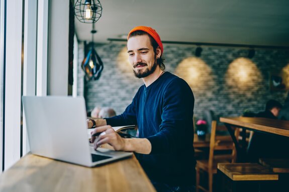 Positive caucasian male checking news from networks working remotely on publicity area, man freelancer reading information on web page looking on screen of laptop computer connected to wifi internet