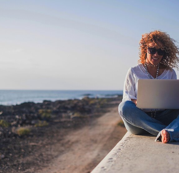 Happy lifestyle digital nomad young cheerful woman work outdoor with laptop computer - people and modern technology job and communication related - alternative office at the beach