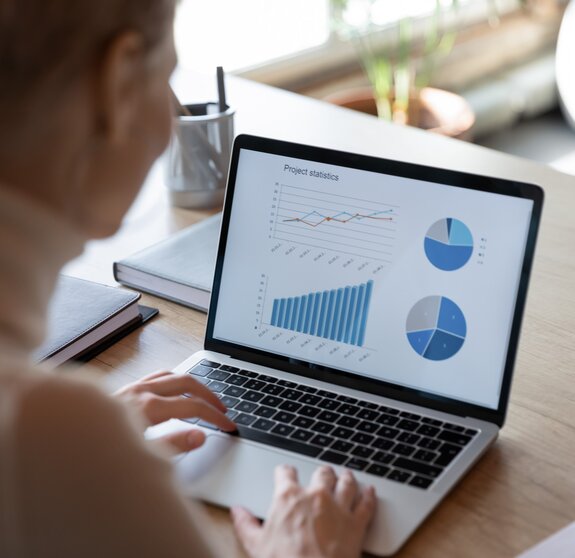 Charts, graphs, analysis sales information on laptop screen view over financier shoulder, visual representation of financial data, using helpful app for make analyze easier. Project statistics concept