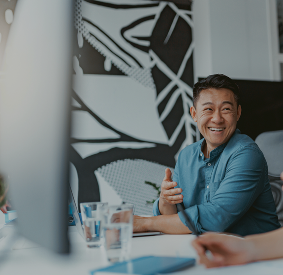 Handsome asian businessman working on laptop sitting in coworking on colleagues background