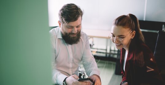 Work partners sitting in office surfing phone in company