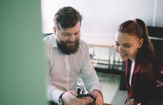 Work partners sitting in office surfing phone in company