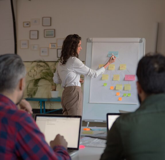 Manager presenting project strategy to coworkers, drawing hierarchy chart. Business colleagues in casual working together in contemporary office space. Presentation concept 