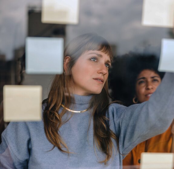 Two young businesswomen brainstorming using adhesive notes in an office