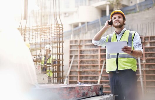 Ingenieur mit einem Tablet in der Hand telefoniert auf einer Baustelle