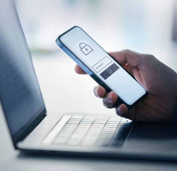 Man holding smart phone with data security on display at office