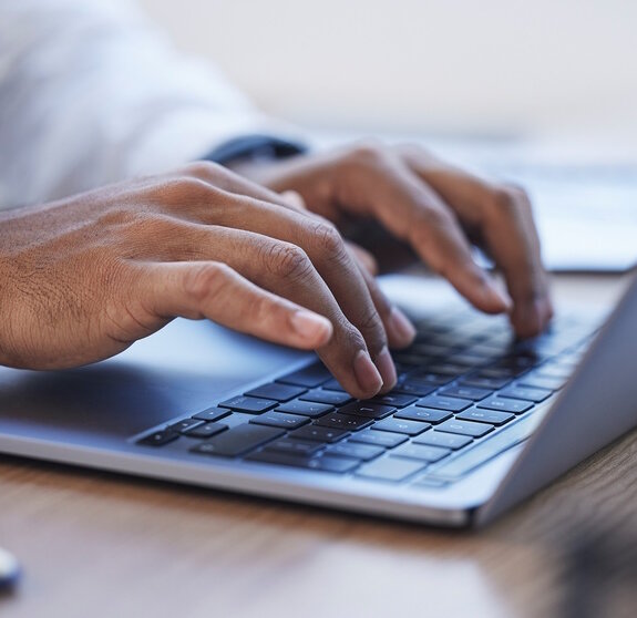 Laptop, office and hands typing at desk for online documents, writing email and business proposal. Technology, networking and zoom of businessman on computer for research, report and website review