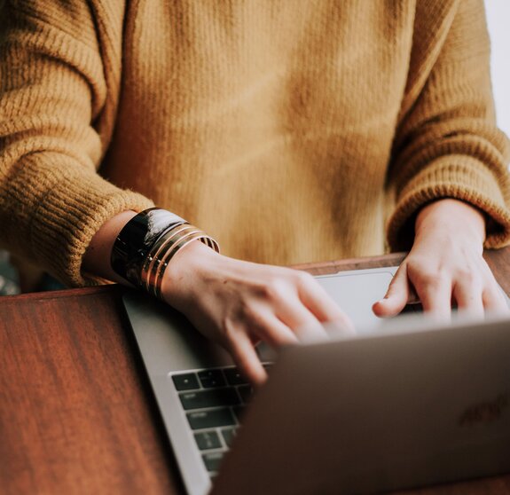 Frau im Pullover arbeitet am Laptop