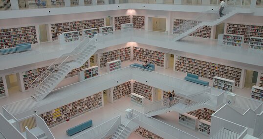 Ein Gang mit deckenhohen Regalen zu beiden Seiten, in denen ungeordnet Bücher gestapelt sind.