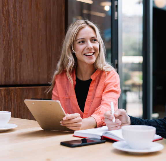 Cheerful caucasian female student looking a her male friend discussing learning project on cafe break, prosperous young man and woman employees talking to each other about business ideas on meeting